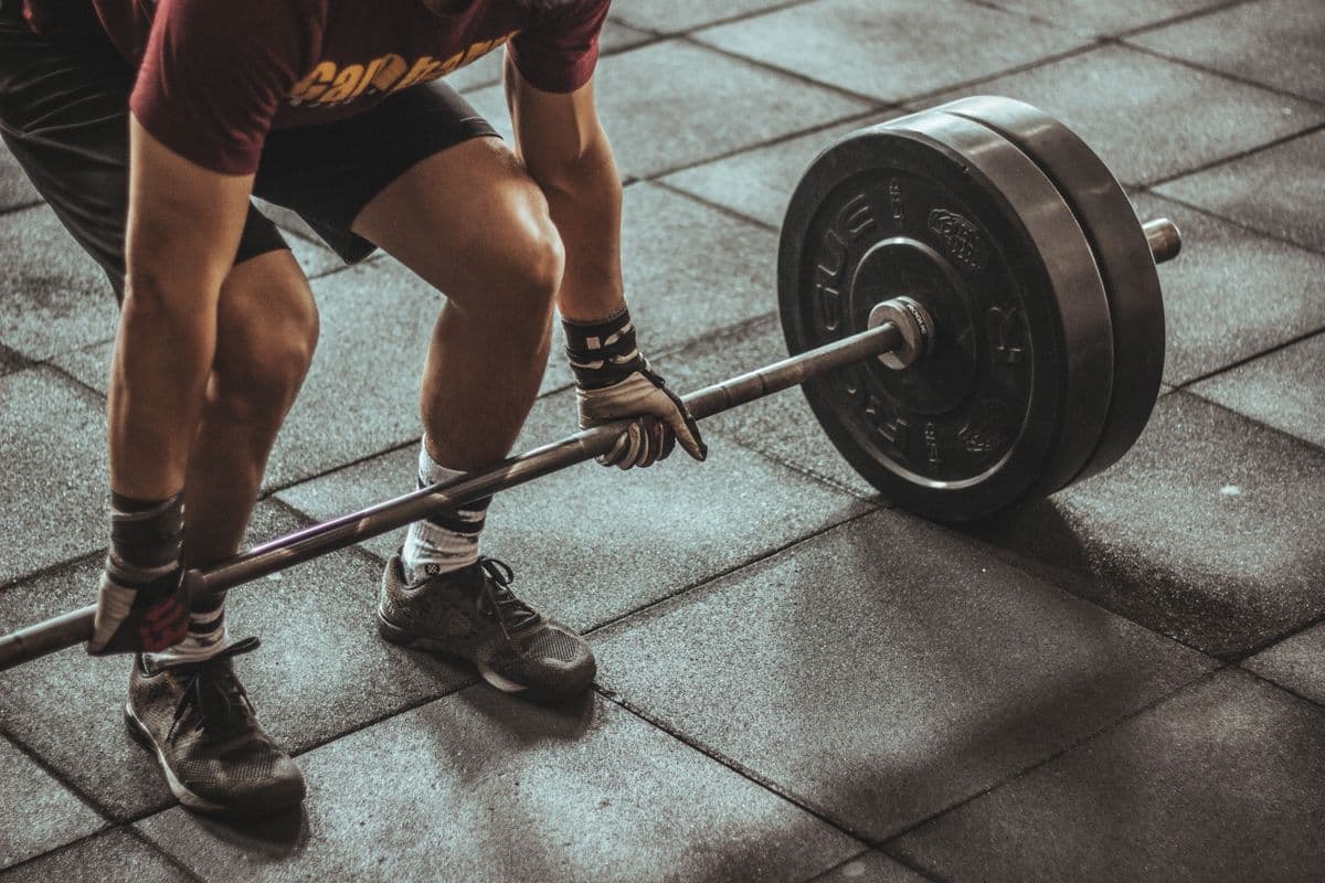 Athlete gripping a loaded barbell on a gym floor, preparing for a lift
